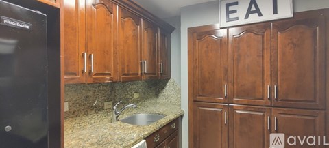 A kitchen with wooden cabinets and a black refrigerator.