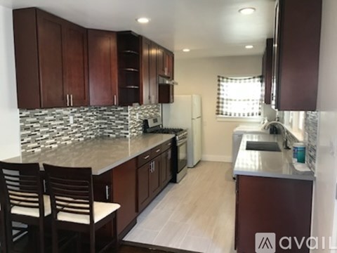 A kitchen with brown cabinets and a stone backsplash.