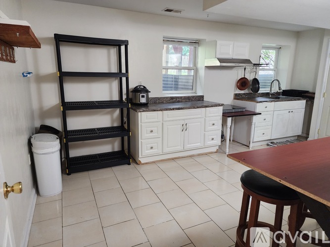 A kitchen with white cabinets and a black shelf unit.