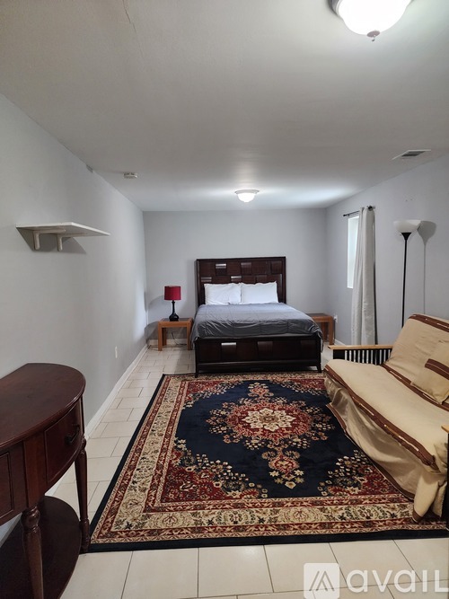 A bedroom with a bed, a couch, and a rug.