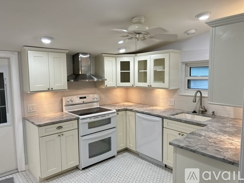 A kitchen with white cabinets and a marble countertop.