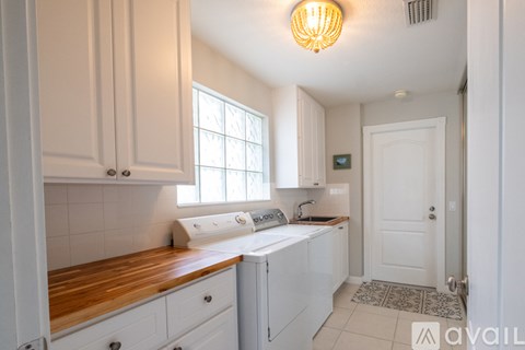 A kitchen with white cabinets and a wooden counter top.