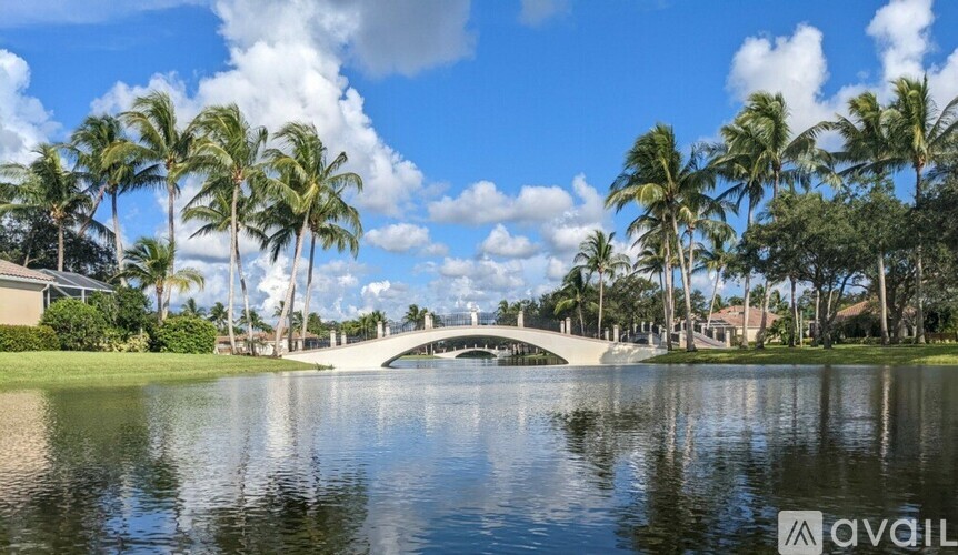 A bridge over a calm body of water with palm trees in the background.