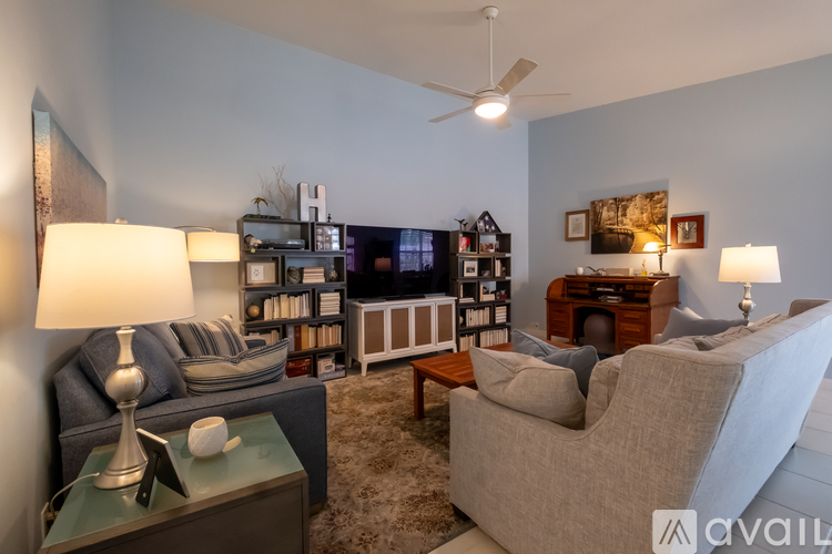 A living room with a grey couch, a white armchair, a green side table, and a bookshelf.