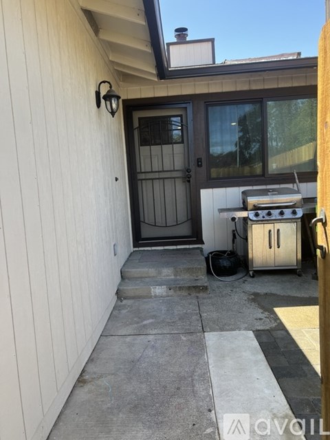 A small outdoor patio with a grill and a door.