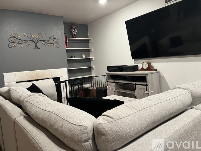 A living room with a white couch and a television mounted on the wall.