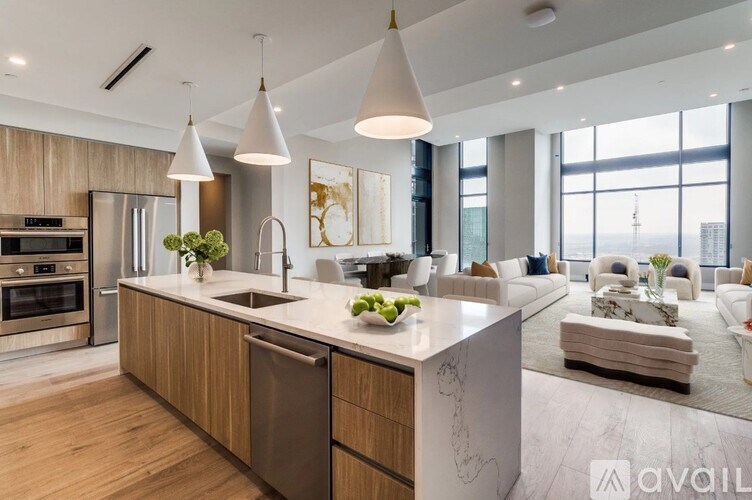 A modern kitchen with a large island and pendant lights.