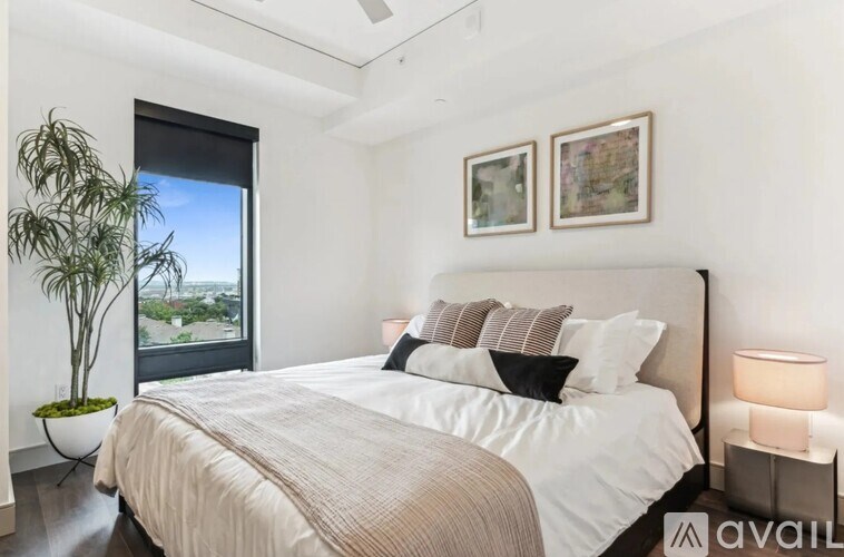 A bedroom with a large bed and a plant by the window.