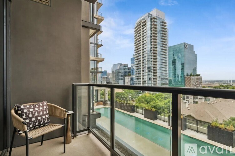 A balcony with a chair and a pillow with a view of the city.