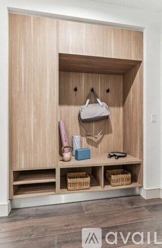 A wooden closet with a coat hanging on the hook and a pair of shoes on the floor.