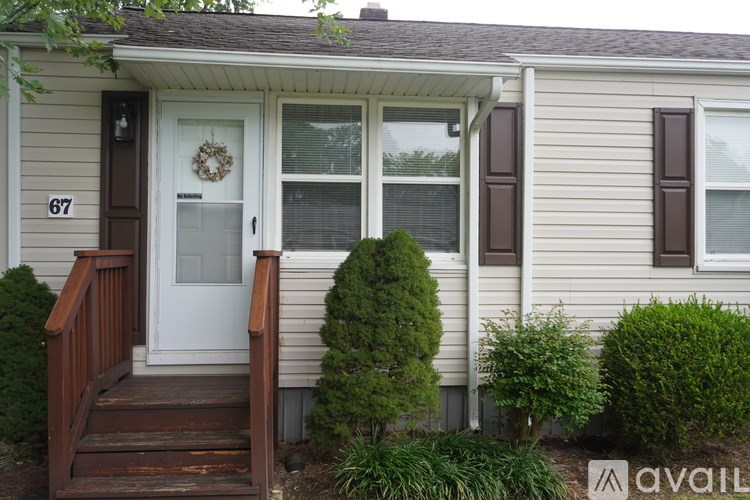 A house numbered 67 has a white door and a wreath on it.