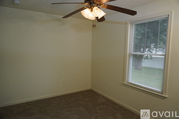 A room with a ceiling fan and a window with blinds.