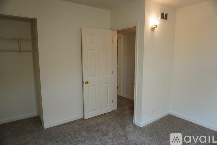A room with a white door and a grey carpet.