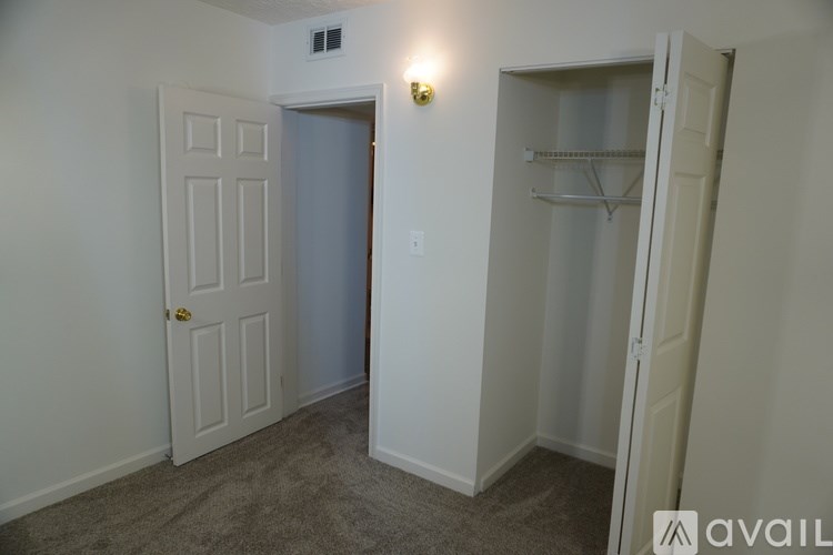 A room with a white door and a grey carpet.