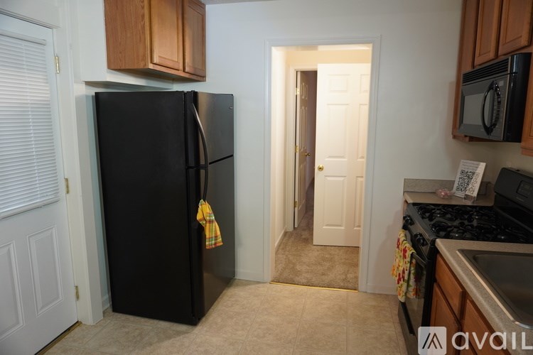 A black refrigerator with a yellow towel hanging on it.