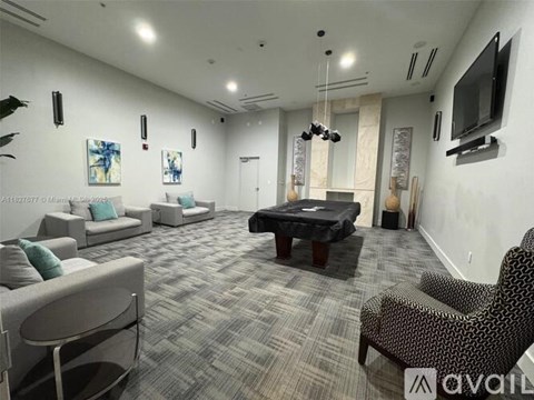 A living room with a grey carpet and a black sofa.