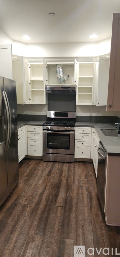 A kitchen with a stainless steel refrigerator and wooden flooring.