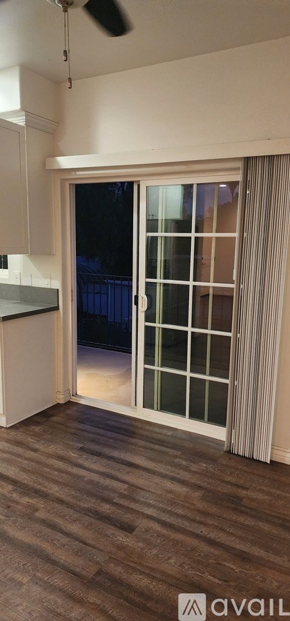 A room with a sliding glass door and wooden flooring.
