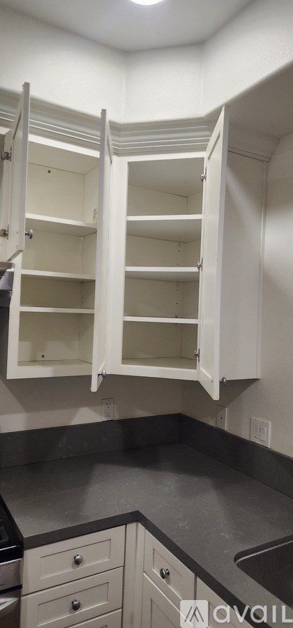 A kitchen with white cabinets and a grey countertop.