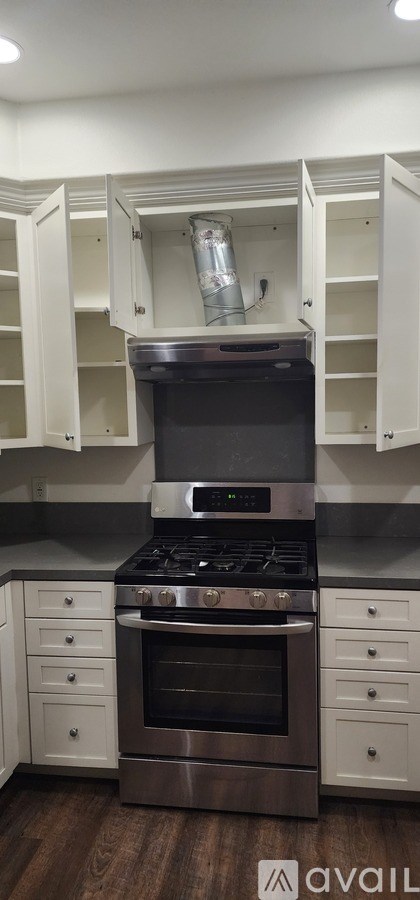 A kitchen with a stove top oven and white cabinets.