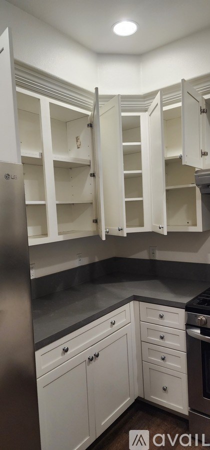 A kitchen with white cabinets and a stainless steel refrigerator.