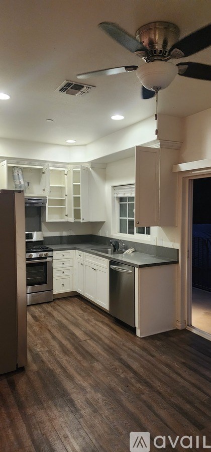 A kitchen with a fan on the ceiling and wooden flooring.