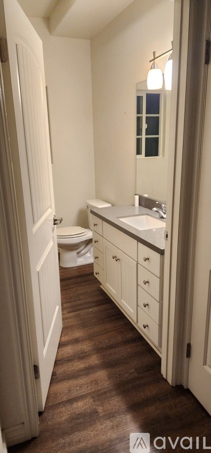 A bathroom with a toilet, sink, and mirror.