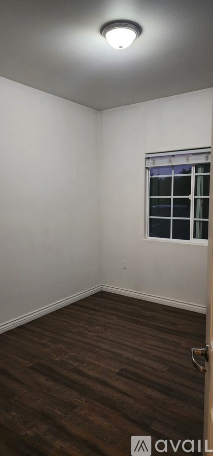 A room with a window and a wooden floor.