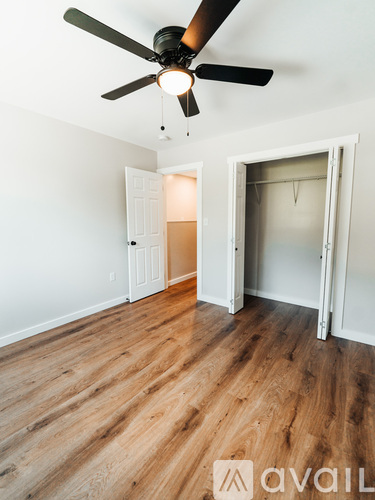 A room with a ceiling fan and wooden flooring.