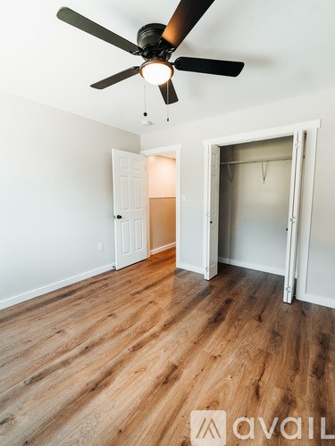 A room with a ceiling fan and wooden flooring.