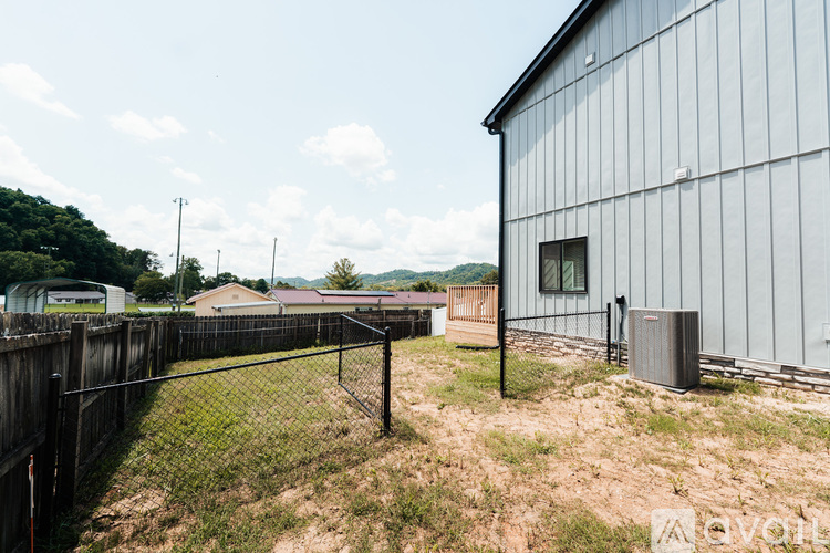 A metal fence surrounds a grassy yard with a building in the background.