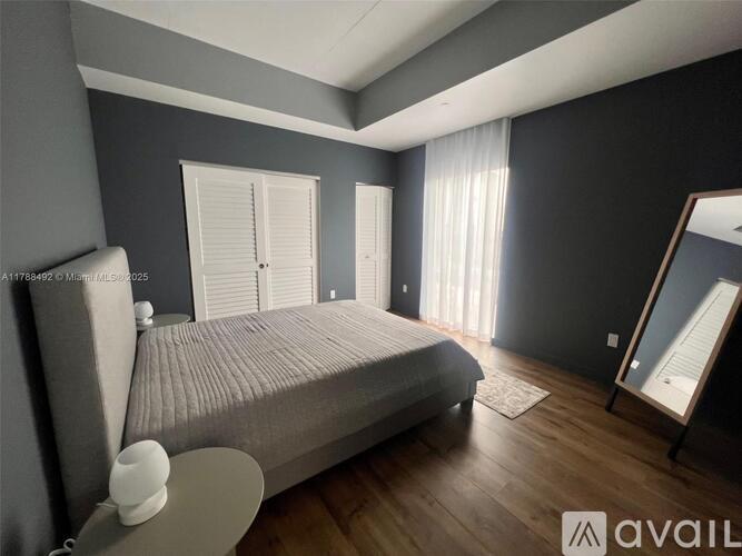 A bedroom with a large bed, a nightstand, and a mirror.