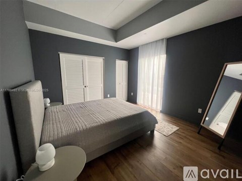 A bedroom with a large bed, a nightstand, and a mirror.