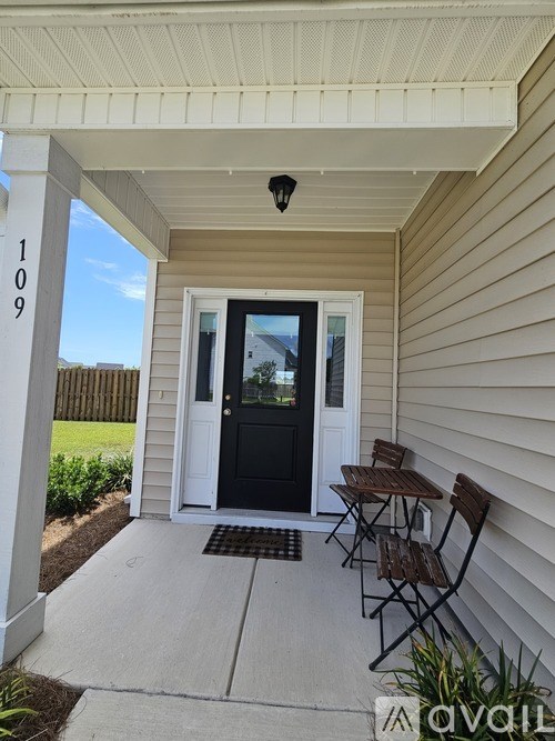 A black door is on the front of a house with a white porch.