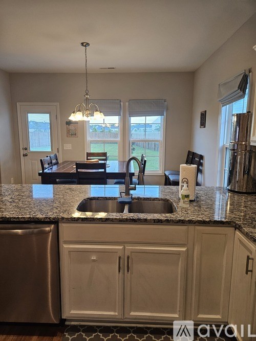 A kitchen with a granite countertop and a stainless steel dishwasher.