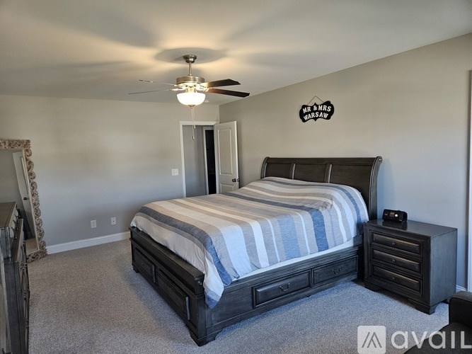 A bedroom with a bed, dresser, and ceiling fan.