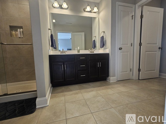 A bathroom with a large mirror, a sink, and a shower.