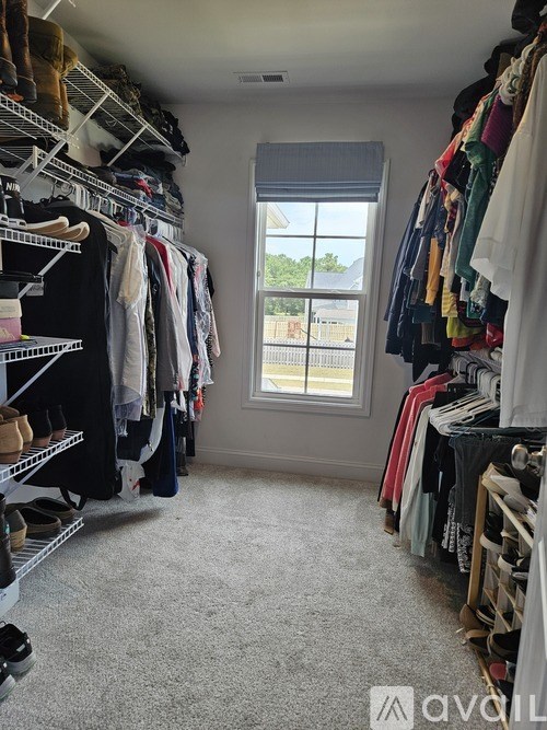 A room with a window and a lot of clothes hanging up.