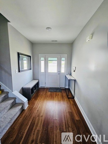 A hallway with wood floors and a staircase.