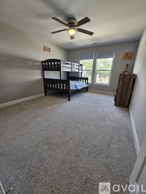 A room with a bunk bed and a ceiling fan.