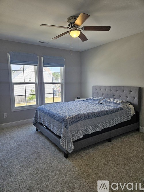 A bedroom with a bed, carpet, and a ceiling fan.