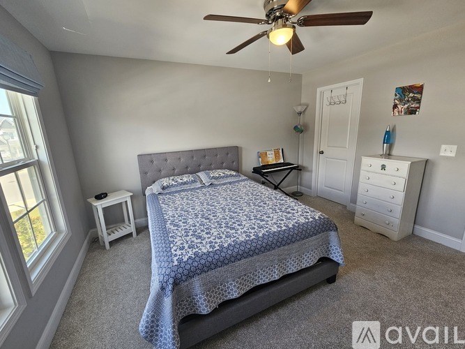 A bedroom with a bed, nightstand, and a ceiling fan.