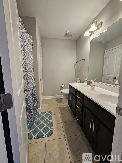 A bathroom with a patterned shower curtain, a sink, a toilet, and a mirror.