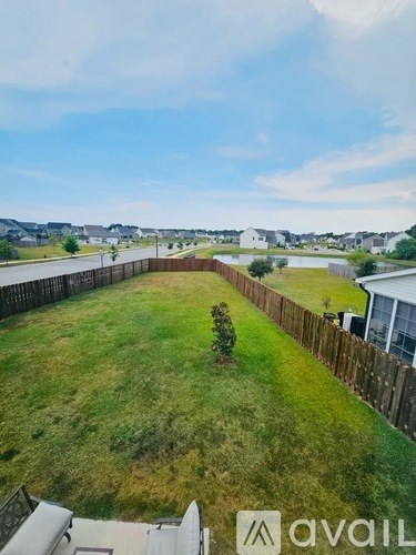 A backyard with a wooden fence and a small tree.