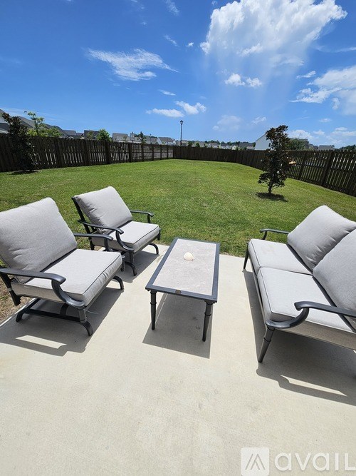 A patio with four chairs and a table is set up on a sunny day.