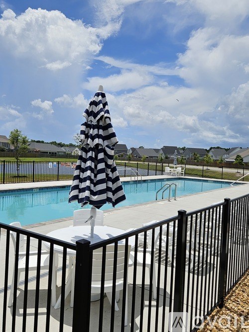 A black and white striped umbrella stands over a pool.