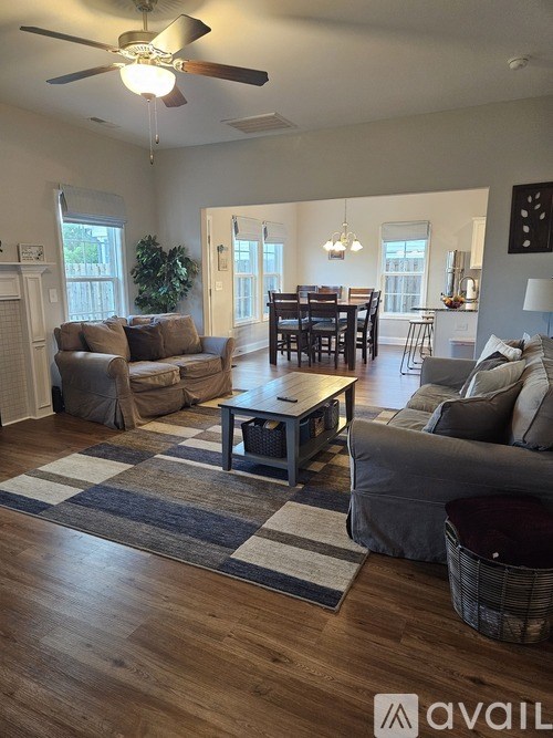 A living room with a brown sofa, a grey armchair, a black and white rug, and a wooden coffee table.