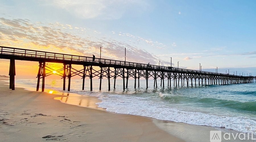 A long pier extends into the ocean at sunset.