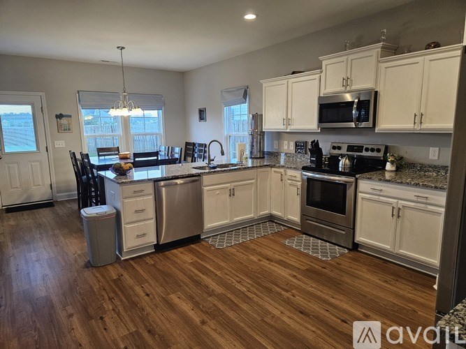 A kitchen with white cabinets and a wooden floor.