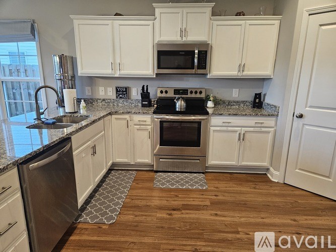 A kitchen with white cabinets and a black stove top oven.